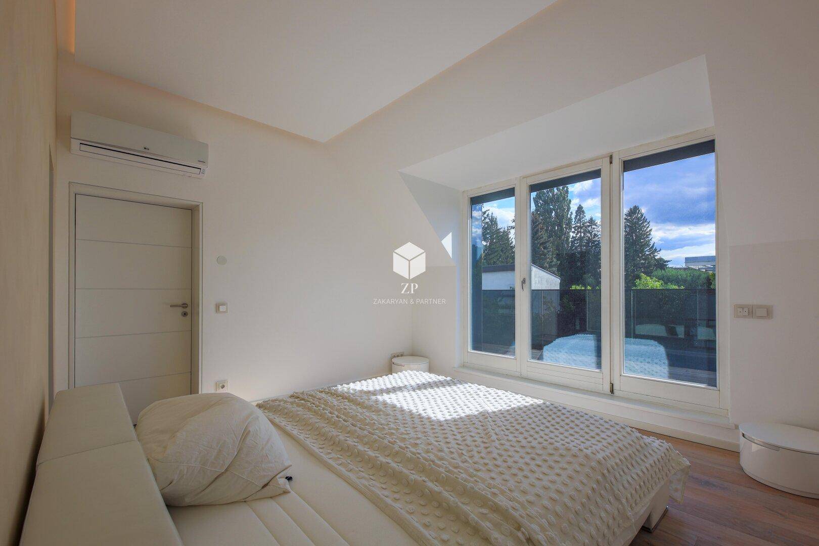 Helles Schlafzimmer mit großem Fenster, Klimaanlage und Holzboden.
