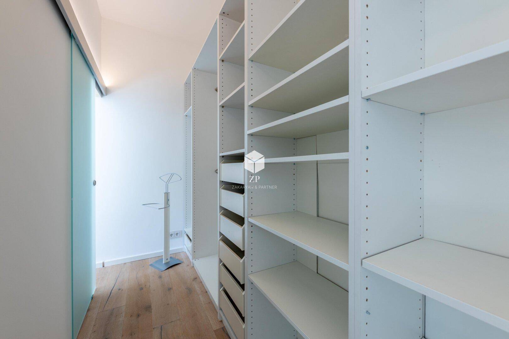Heller begehbarer Kleiderschrank mit umfangreichen Regalsystemen und Stauraum.