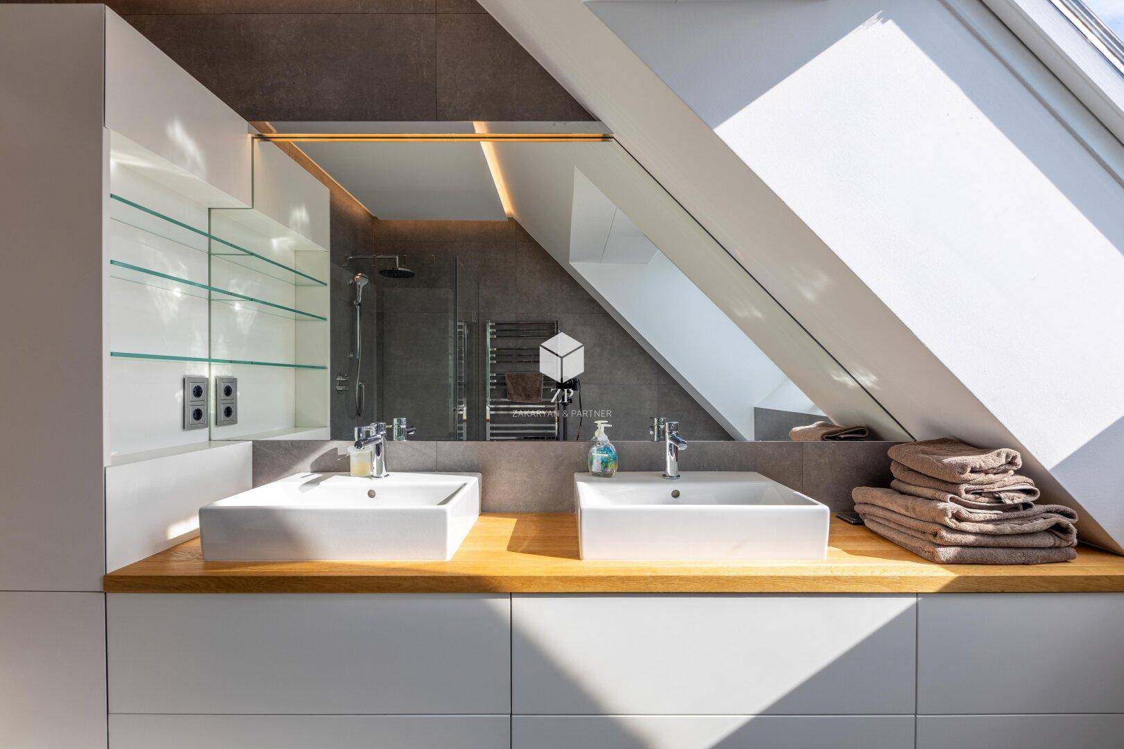 Modernes Badezimmer mit Doppelwaschbecken, großem Spiegel und Dachfenstern für viel Licht.