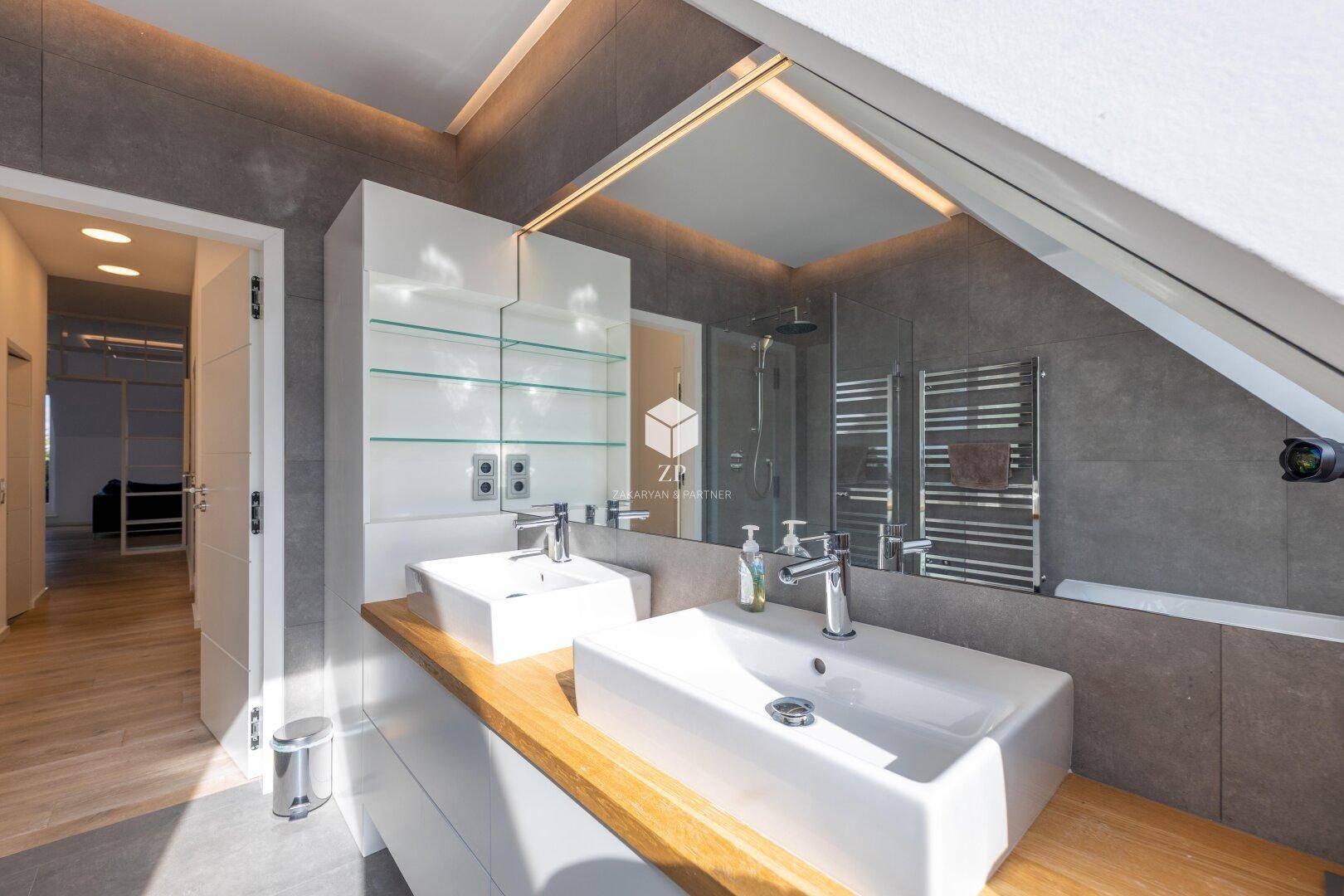 Helles Badezimmer mit Doppelwaschbecken, Holzplatte und integrierten Spiegelschränken.