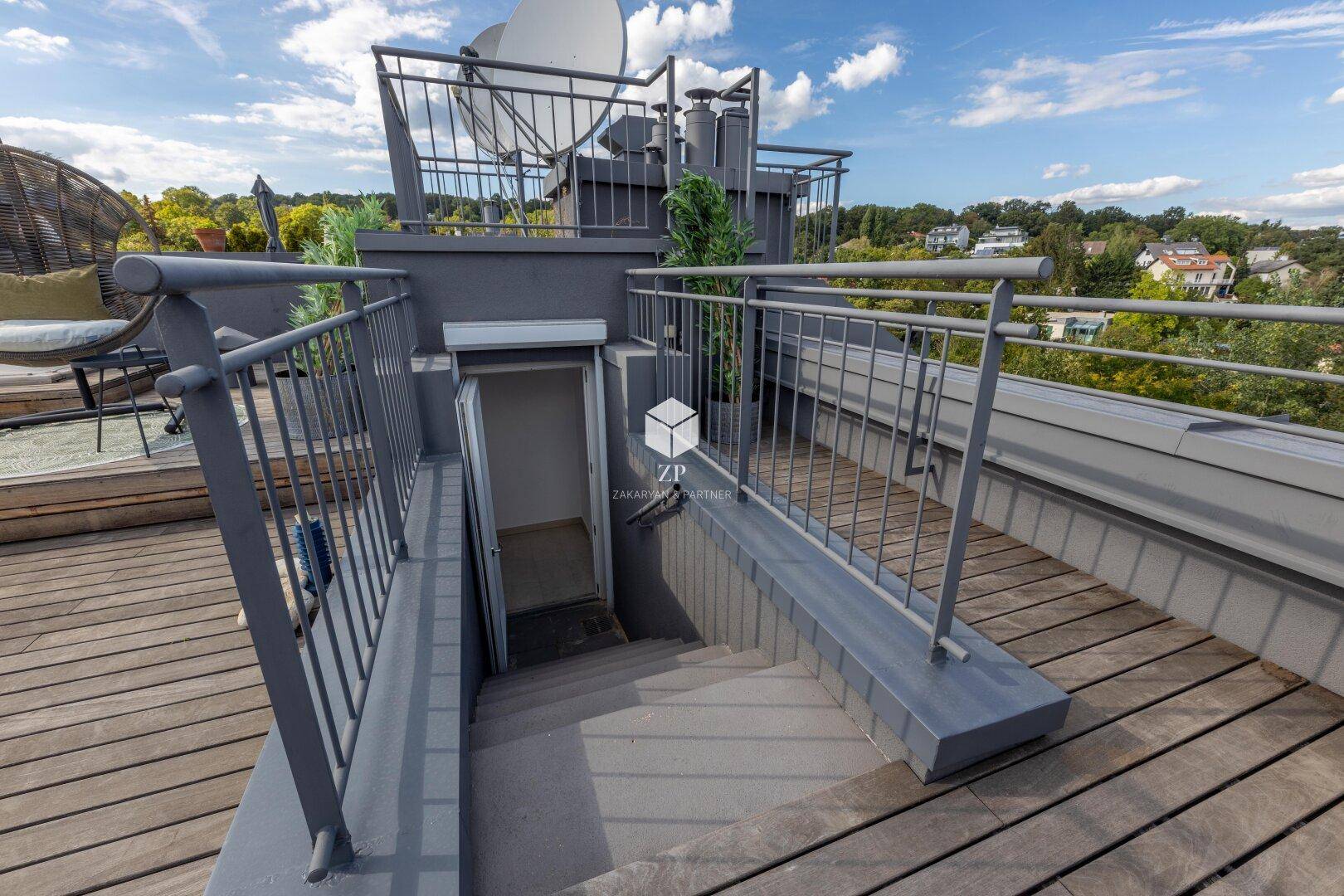 Zugang zur Dachterrasse über eine Außentreppe mit Metallgeländer und Holzboden.