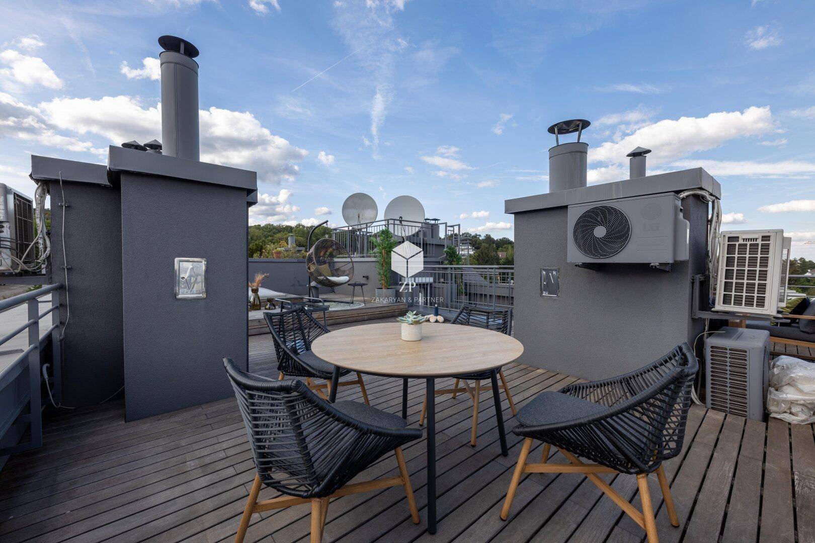 Dachterrasse mit Essbereich und Blick auf die umliegenden Gebäude und Bäume.