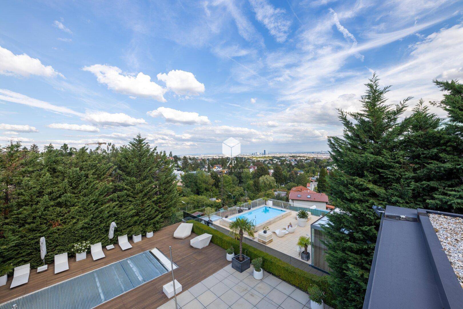 Weitläufige Terrasse mit Blick auf einen großen Poolbereich und die grüne Umgebung.