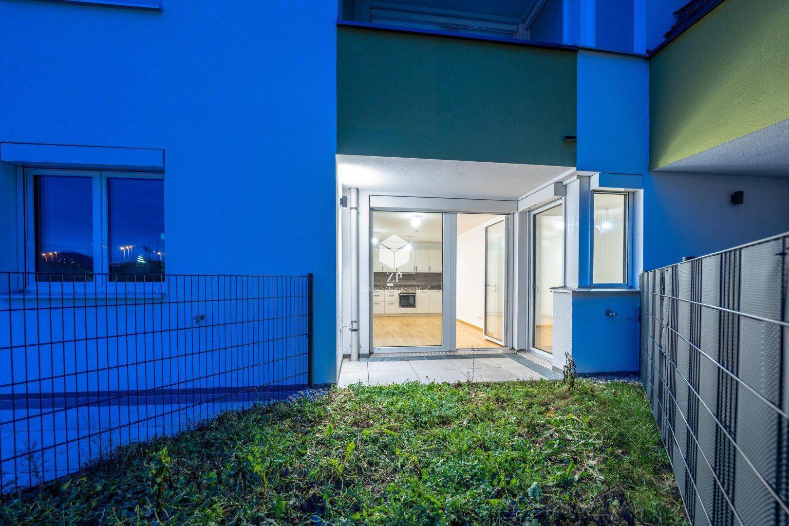 Kleiner privater Gartenbereich mit Terrasse und Zugang zur Wohnung in einem modernen Gebäude.