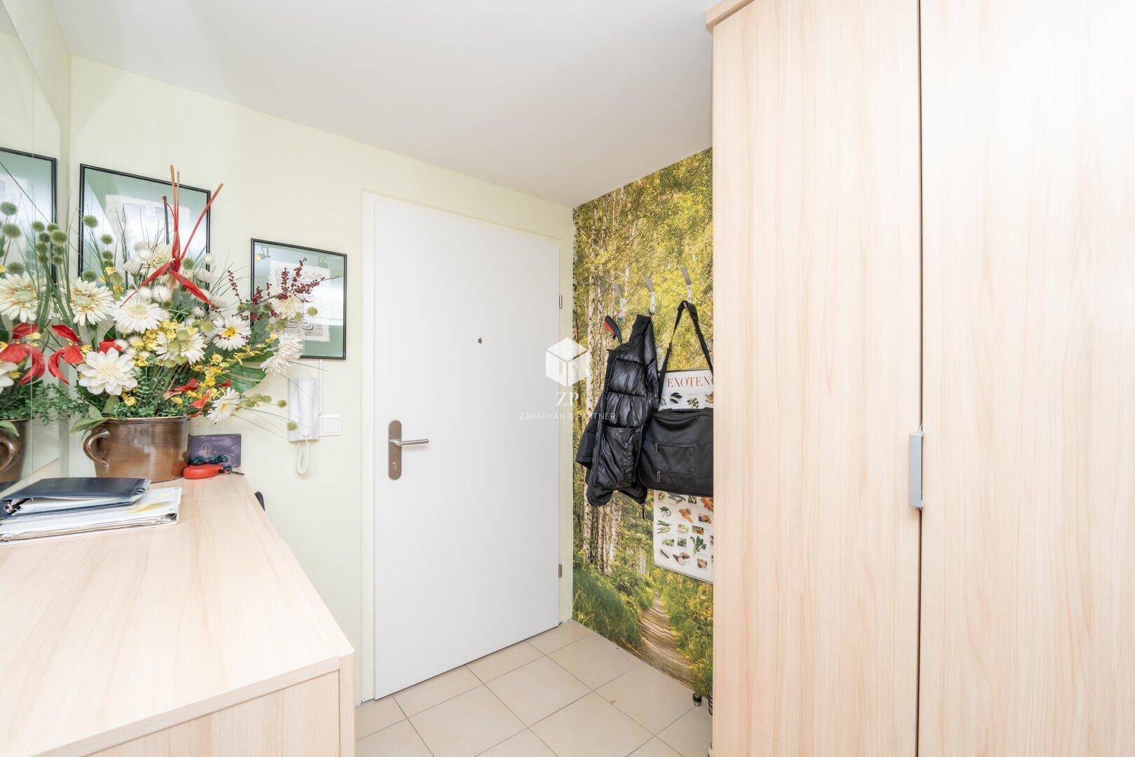 Heller Flur mit Garderobe, Holzschrank und dekorativer Wandtapete.