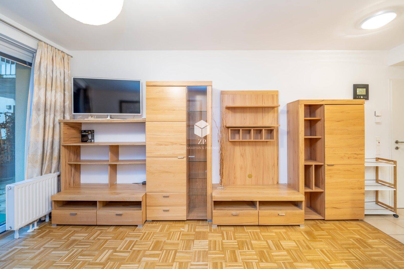 Wohnzimmer mit Parkettboden, Holzregalen und Medienmöbeln.