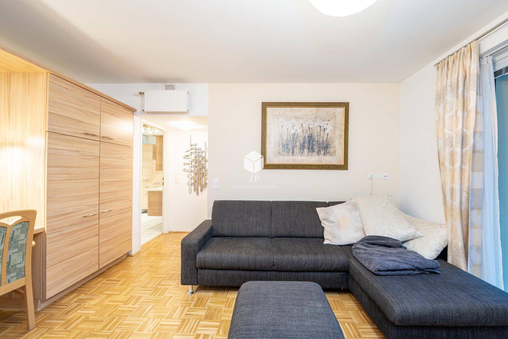 Wohnzimmer mit Sofa, Holzschränken und Blick in den Flur.