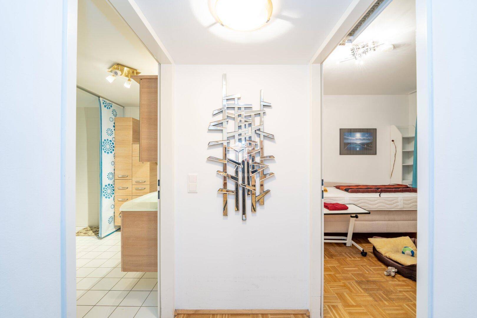 Heller Flur mit dekorativer Wandkunst und Blick in angrenzende Räume.