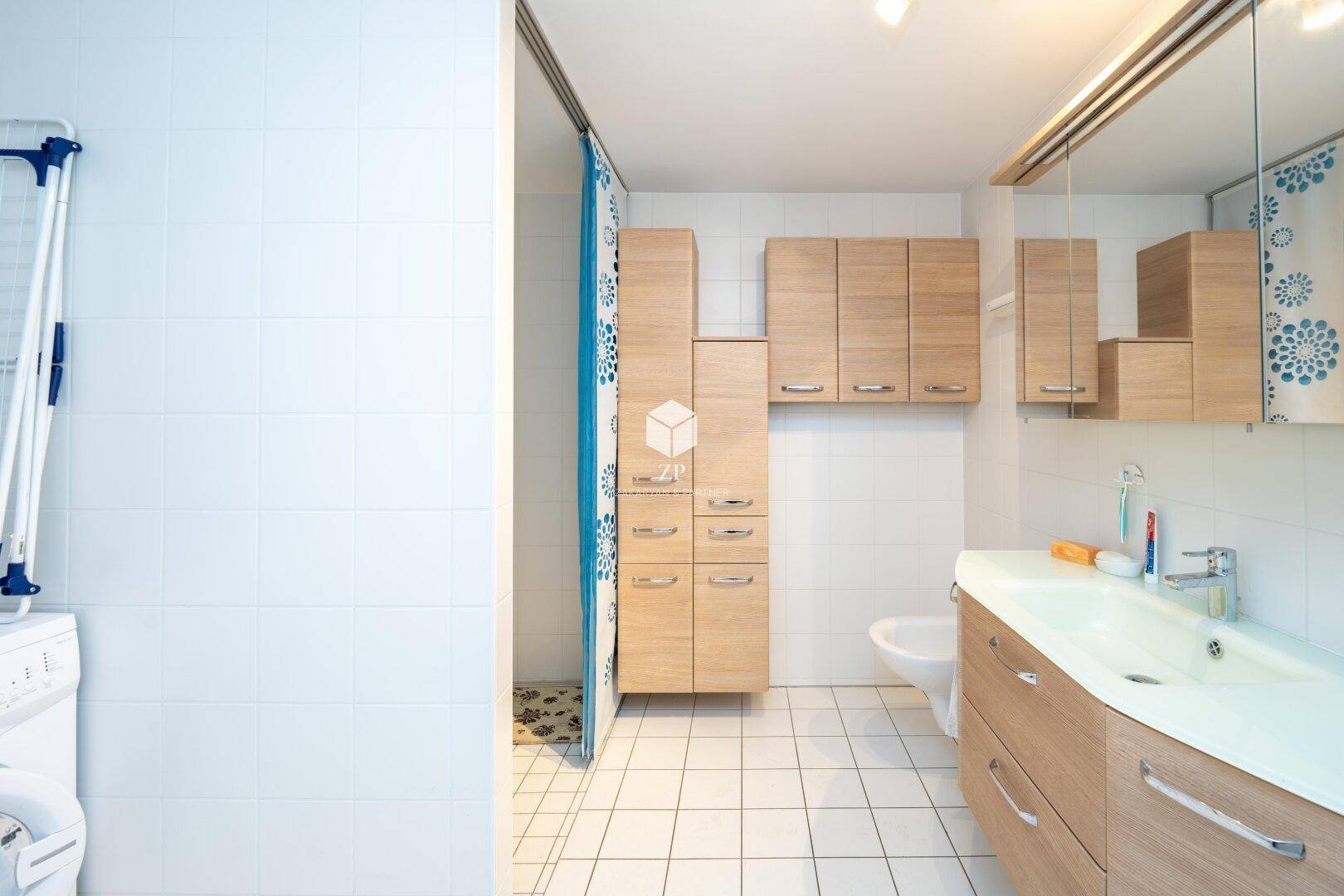 Badezimmer mit Waschtisch, Spiegelschrank und Duschvorhang.