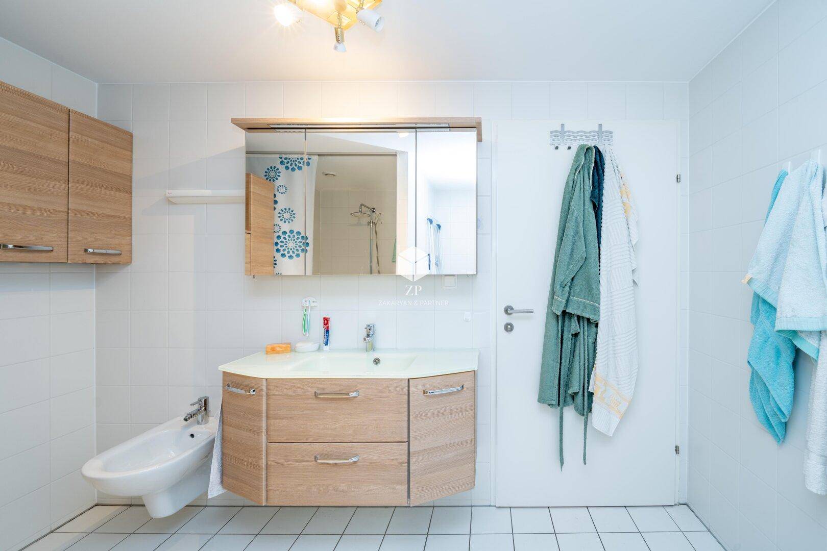 Badezimmer mit modernem Waschtisch, Spiegelschrank und Bidet.
