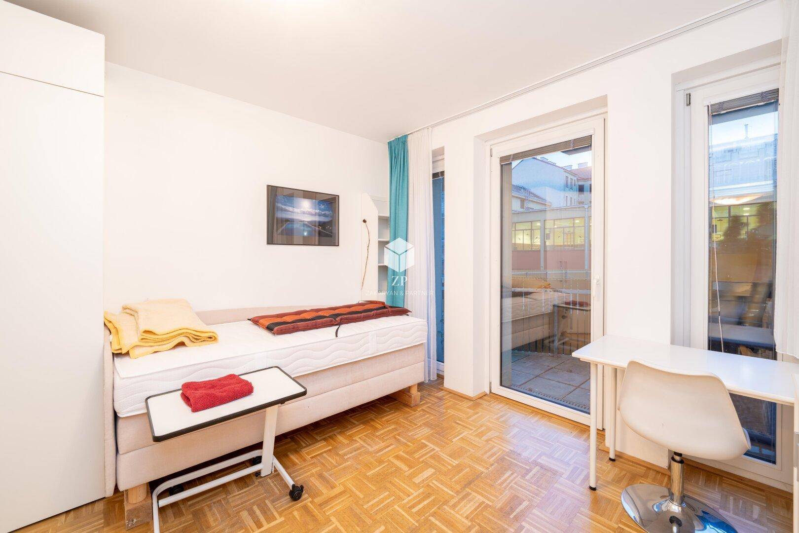 Schlafzimmer mit Einzelbett, Schreibtisch und Blick nach draußen.