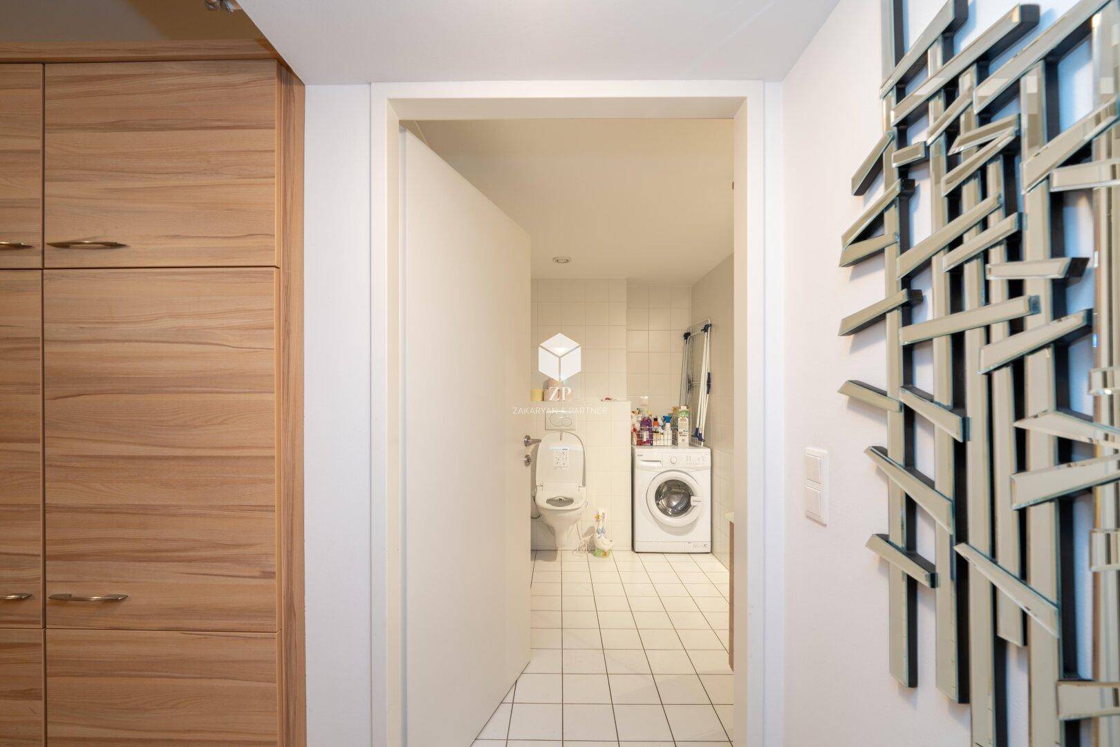 Flur mit Blick auf das Badezimmer und dekorativer Wandkunst.