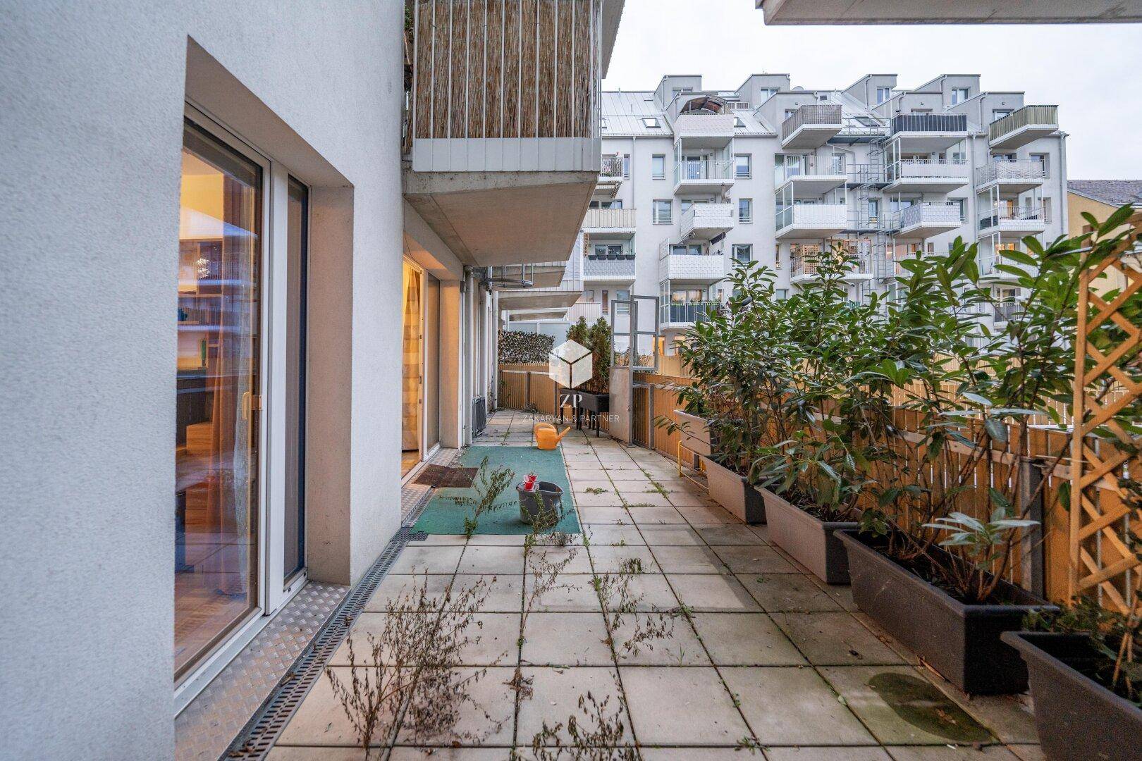 Geräumige Terrasse mit Pflanzkübeln und Blick auf die umliegenden Gebäude.