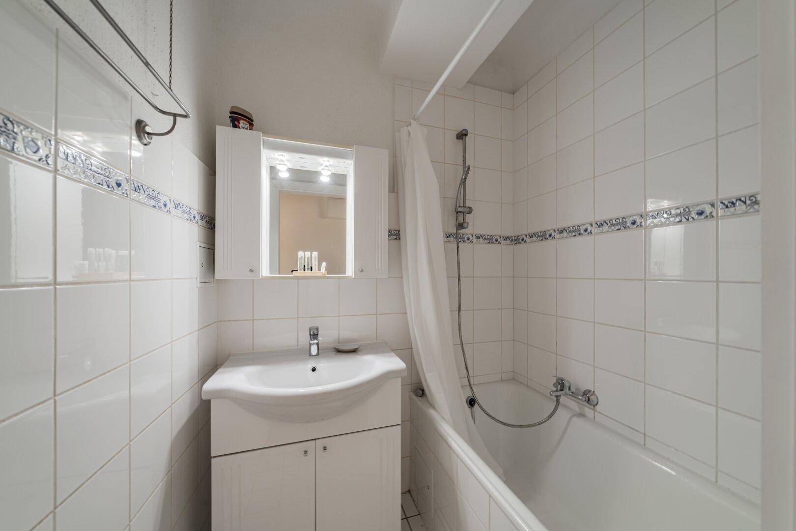 Funktionales Badezimmer mit Badewanne, Duschvorhang und Spiegelschrank, bietet alles Notwendige.