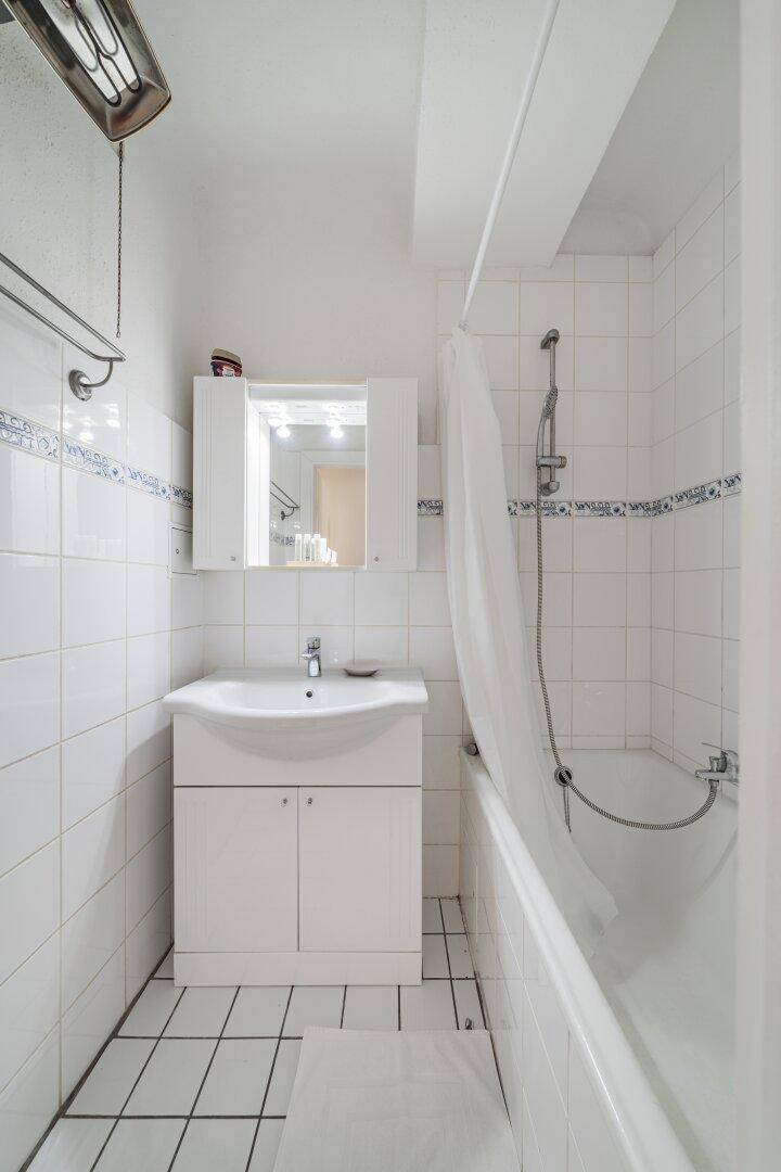 Badezimmer mit Badewanne, Waschbecken und weißen Fliesen mit blauen Akzenten, sauber und gepflegt.