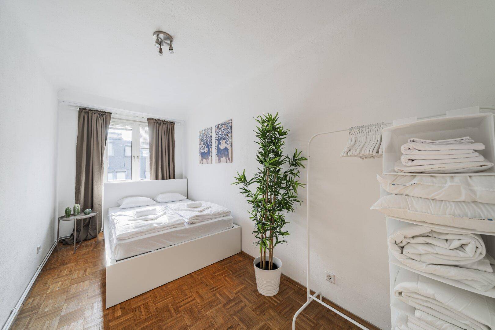 Helles Schlafzimmer mit Doppelbett, Parkettboden und einfacher Einrichtung, sorgt für erholsamen Schlaf.