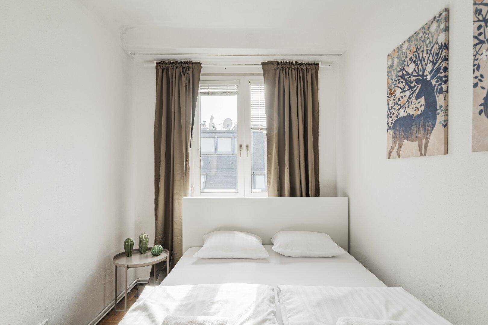 Schlafzimmer mit Doppelbett, Fenster und Blick auf die Umgebung, bietet viel Tageslicht.