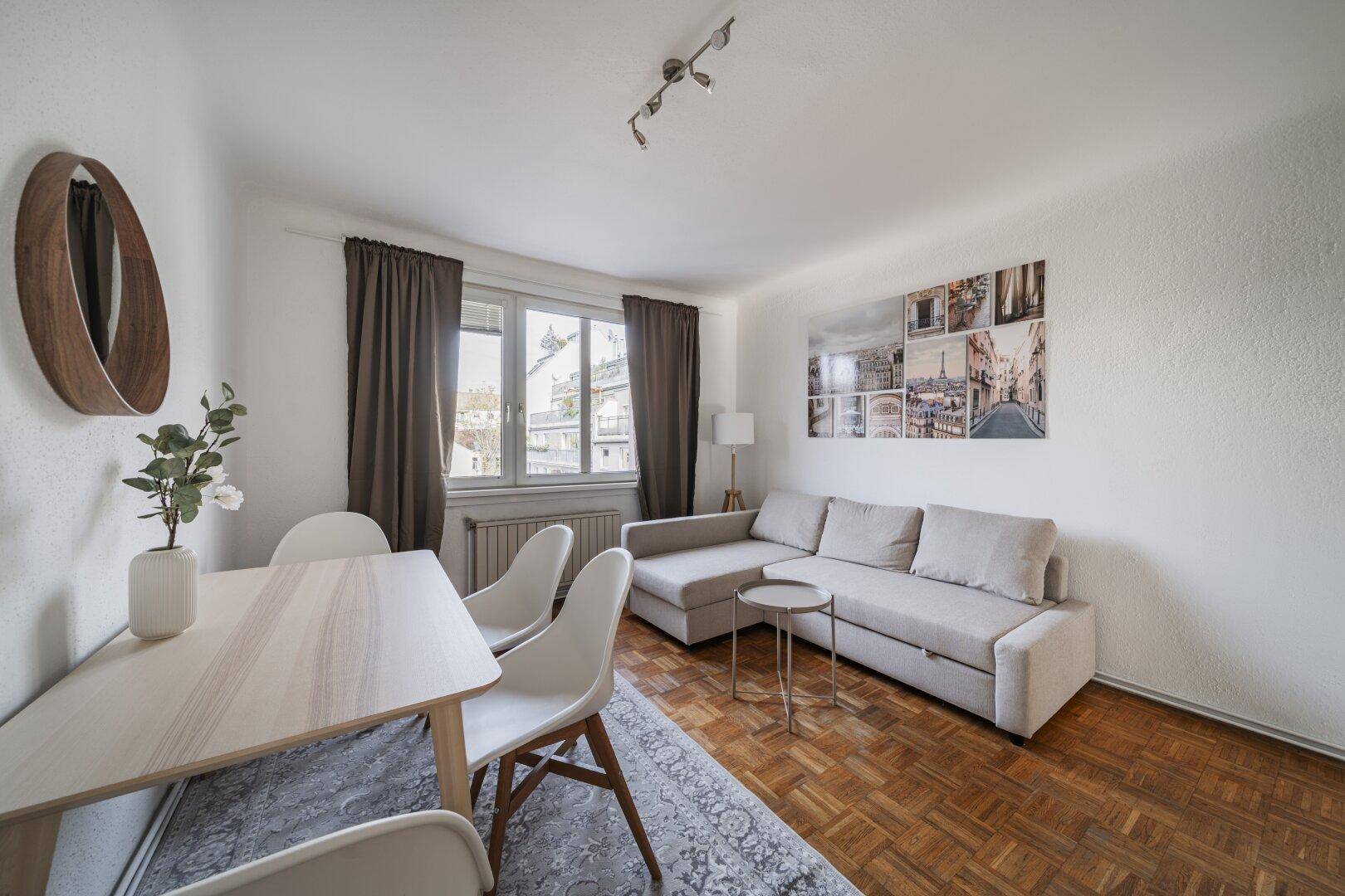 Heller Wohn- und Essbereich mit beigem Sofa, Esstisch und Parkettboden, ideal für gesellige Stunden.