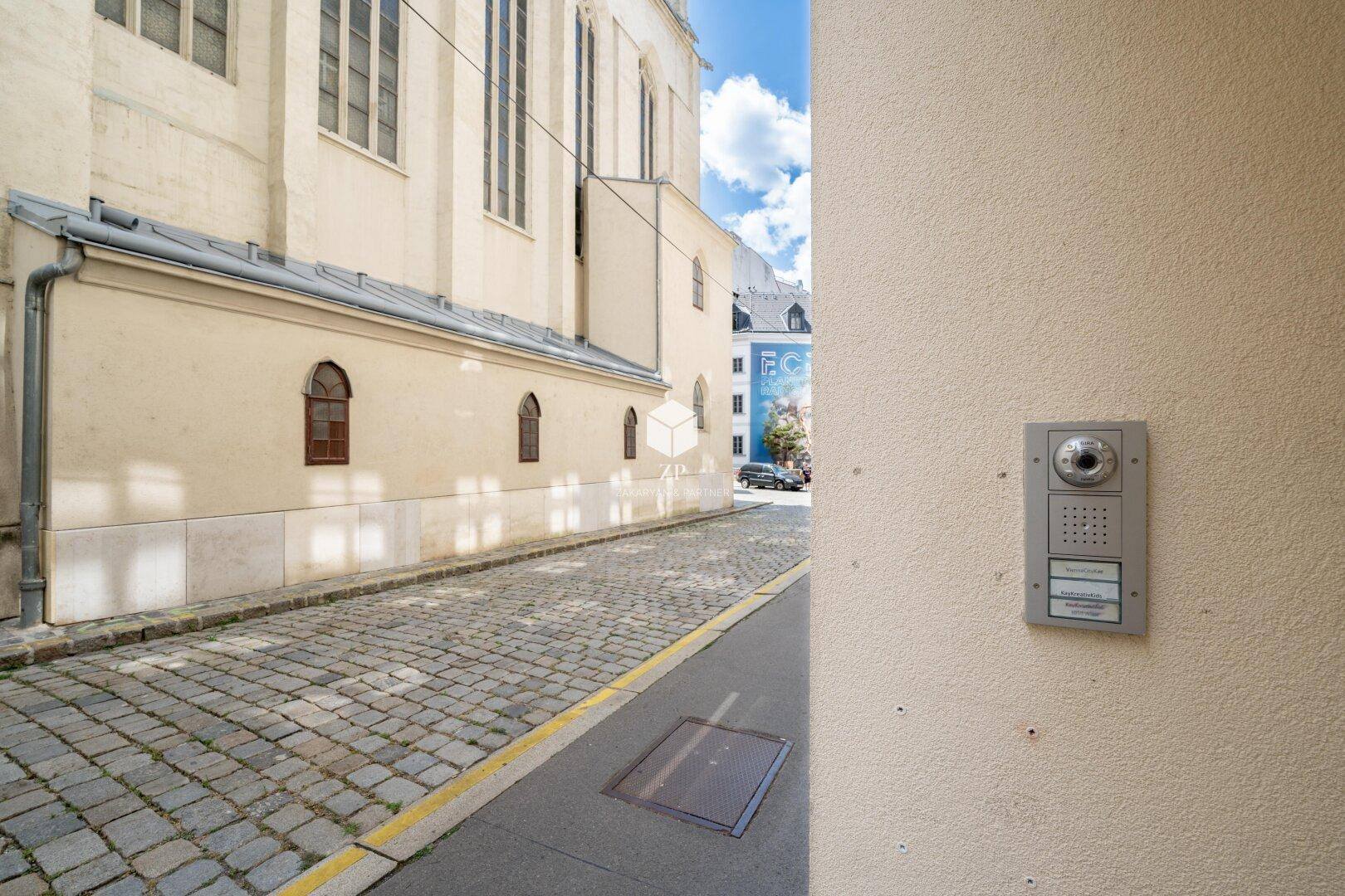 Fassade eines Gebäudes mit Gegensprechanlage an einer gepflasterten Gasse.