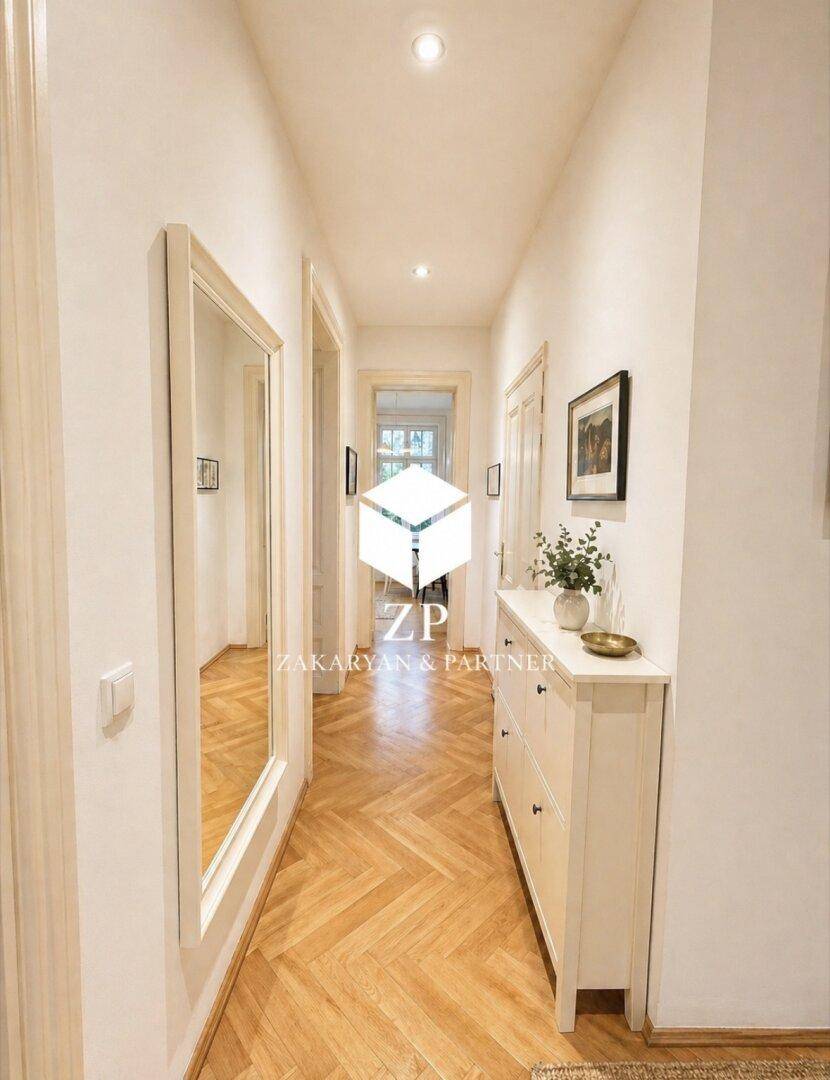 Heller Flur mit Fischgrätparkett, großem Spiegel und einem Sideboard.