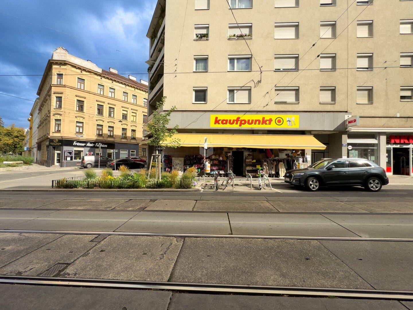 Ansicht eines Eckgebäudes mit einem Geschäft im Erdgeschoss und einer gelben Markise.
