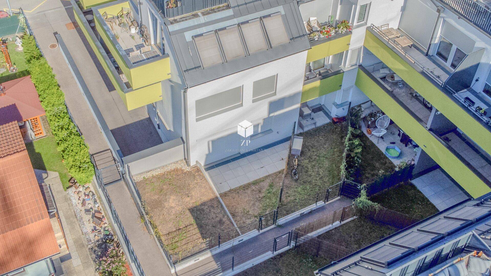 Luftaufnahme eines Wohnkomplexes mit privaten Gärten und Terrassen.