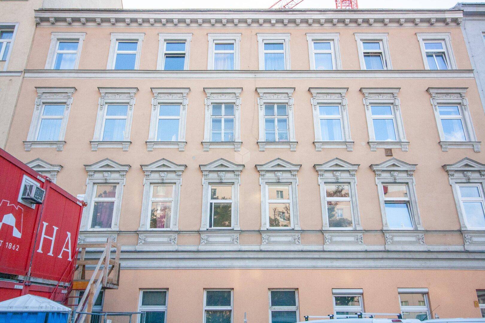 Historische Fassade eines Wohngebäudes mit zahlreichen Fenstern und dekorativen Stuckelementen.