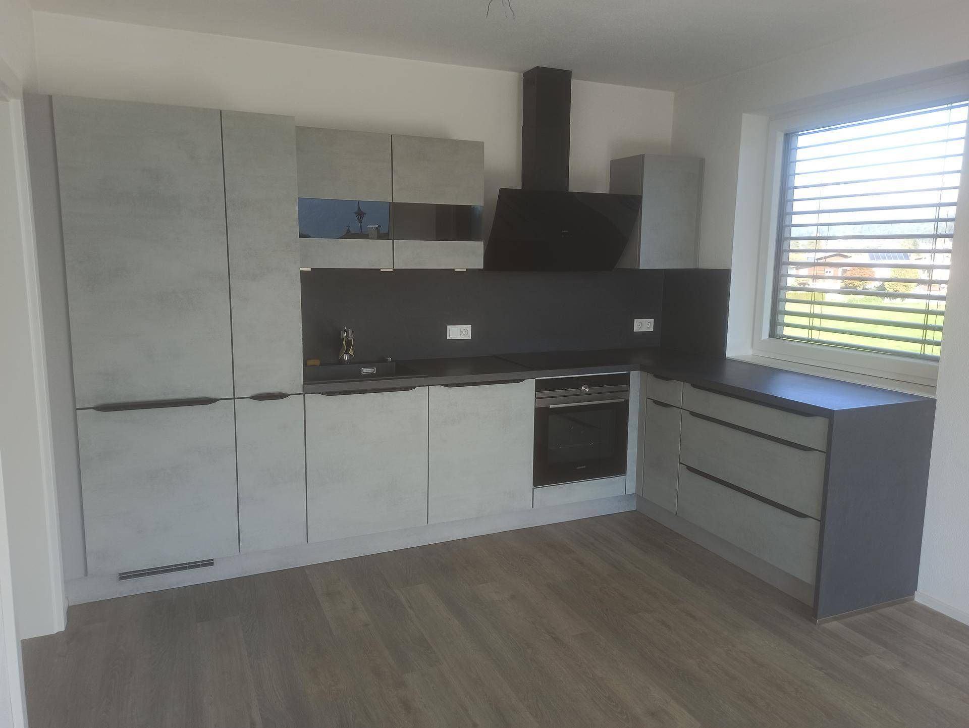 Moderne Einbauküche in Grau mit integrierten Geräten und Fenster für natürliches Licht.