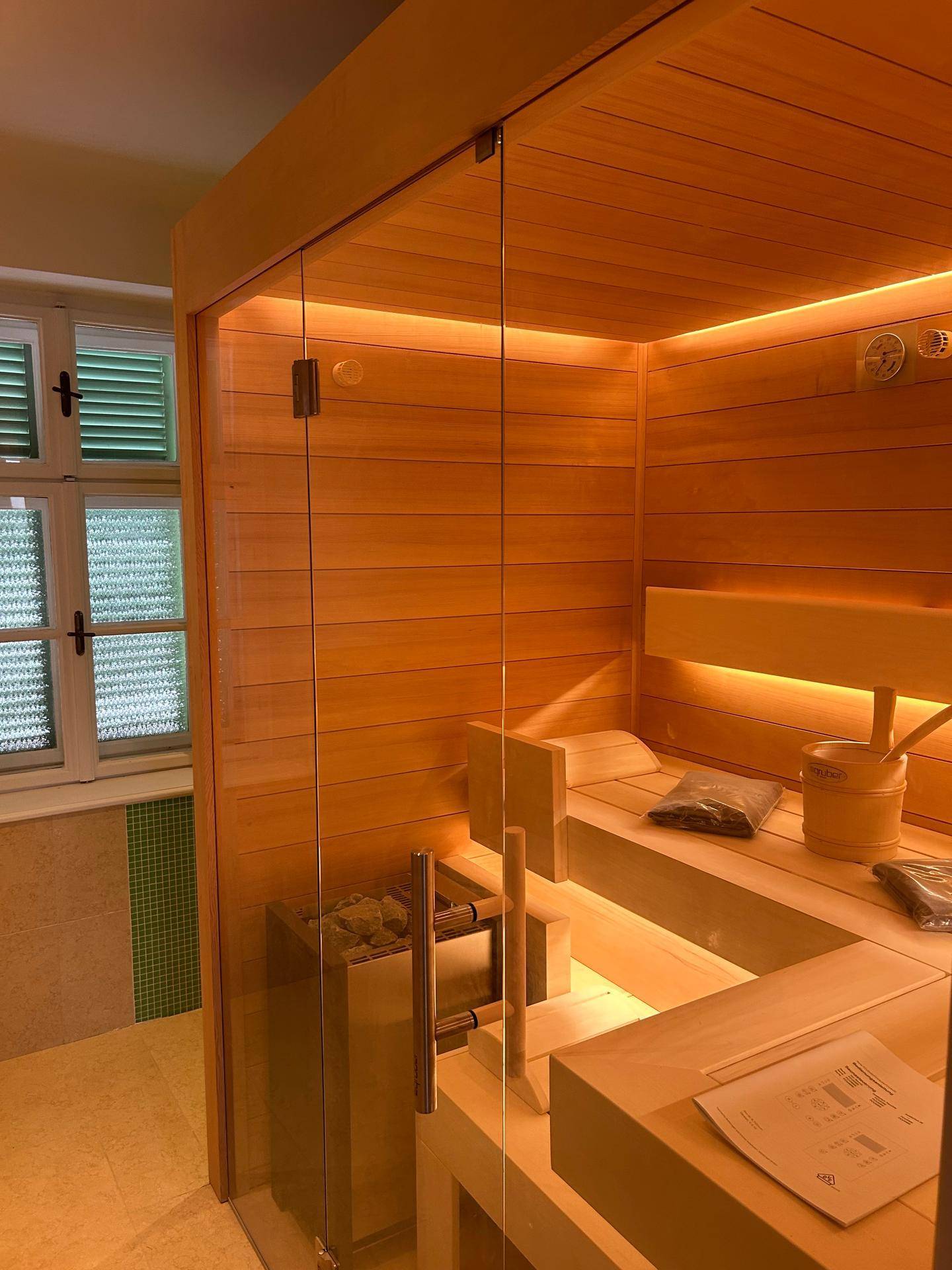 Moderne Sauna mit Holzverkleidung, Glasfront und indirekter Beleuchtung für Entspannung.