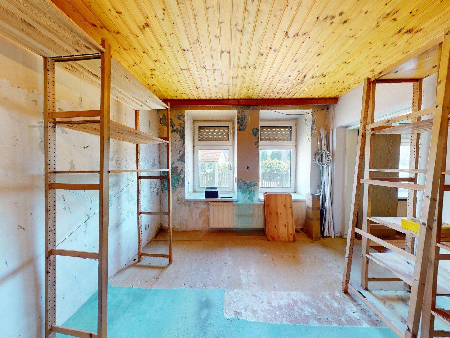 Abstellraum mit Holzdecke und zwei Fenstern, ausgestattet mit einfachen Holzregalen.