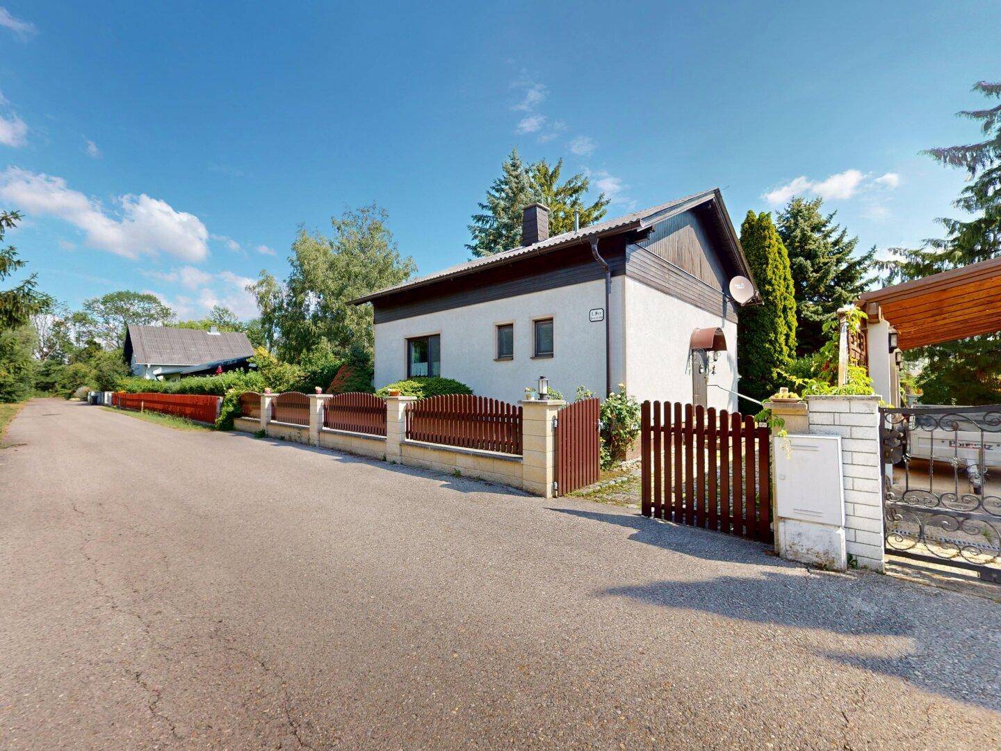 Ansicht des Hauses von der Straße mit einem Holzzaun und einem Eingangstor.
