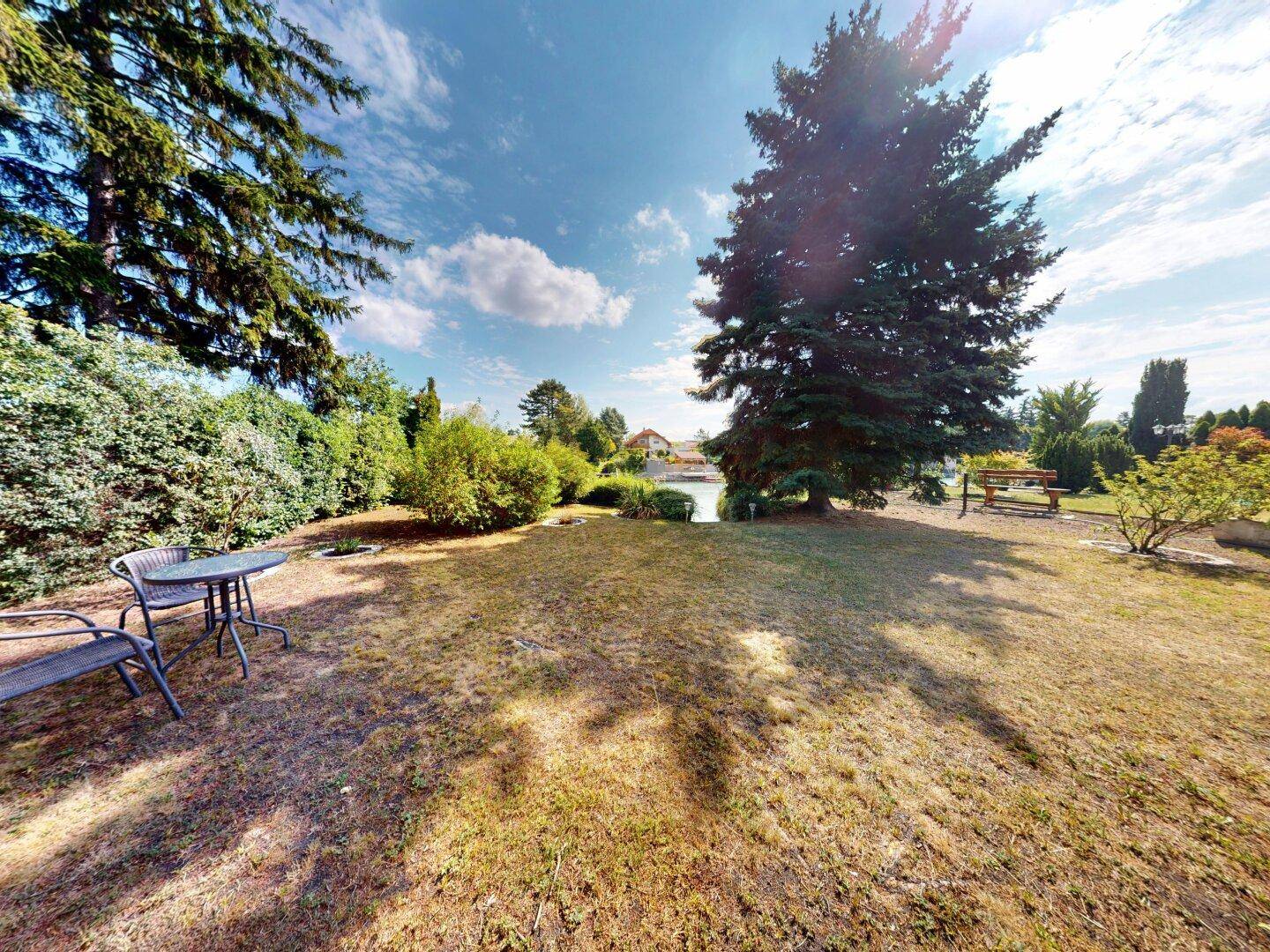 Gartenbereich mit Sitzgelegenheiten und einem weiten Blick auf die umliegende Natur und den See.