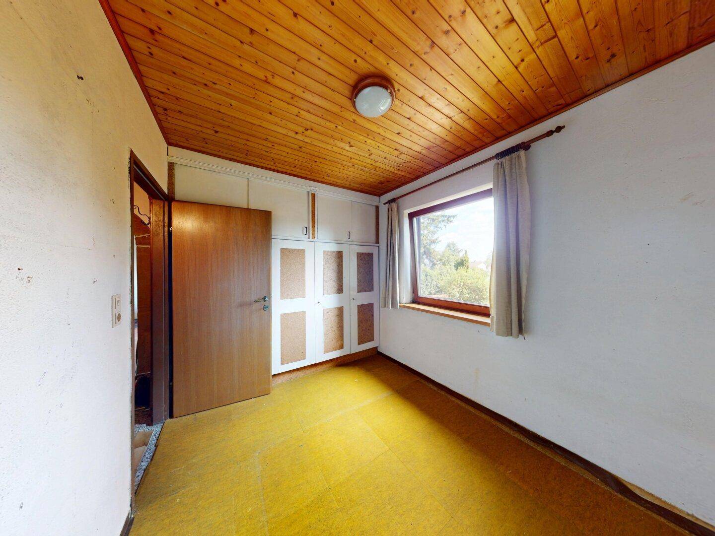 Schlafzimmer mit gelbem Boden, weißen Wänden, Holzdecke und praktischen Einbauschränken.