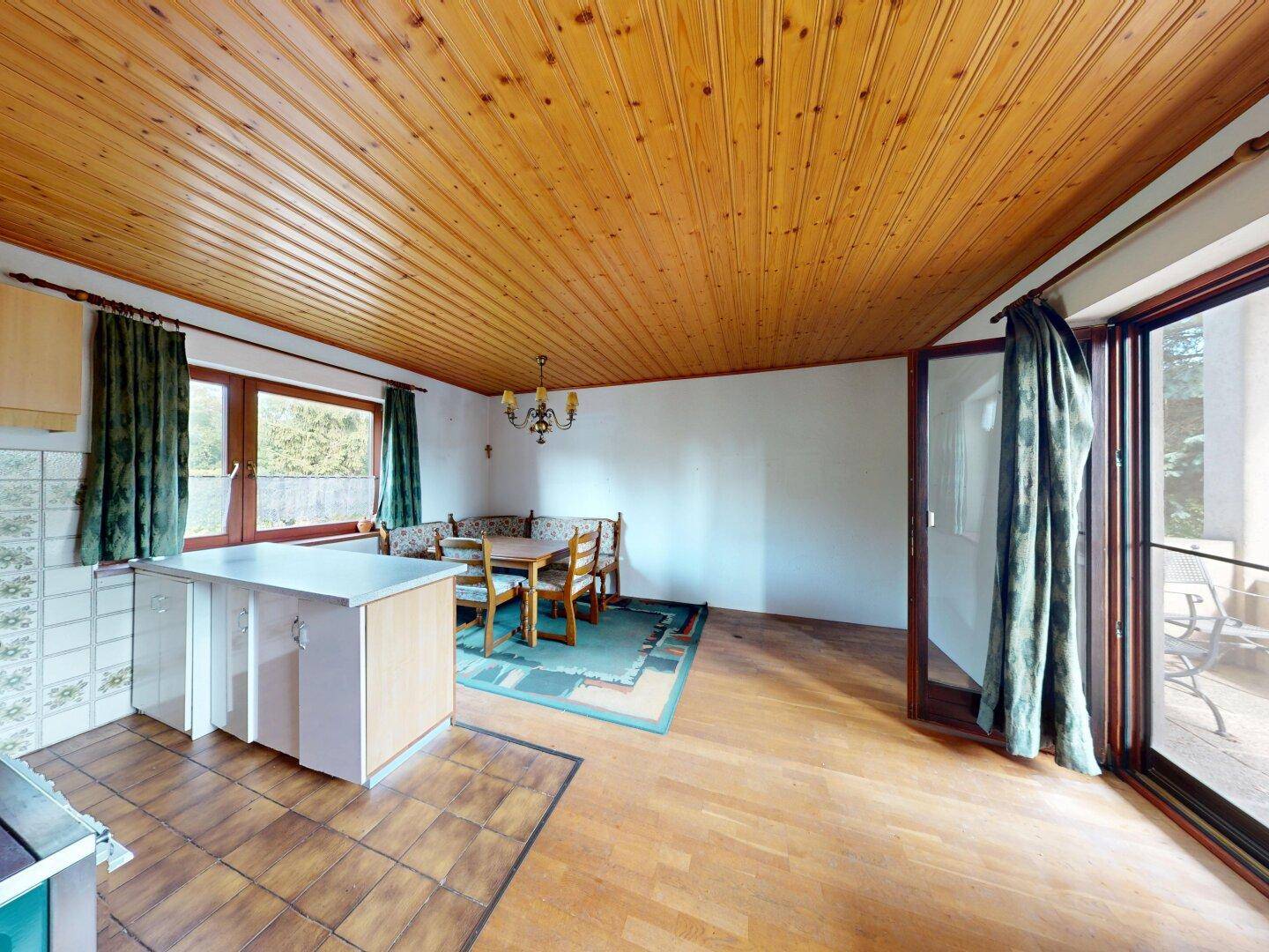 Geräumiger Küchen- und Essbereich mit Holzboden und großem Glaszugang zur Terrasse.