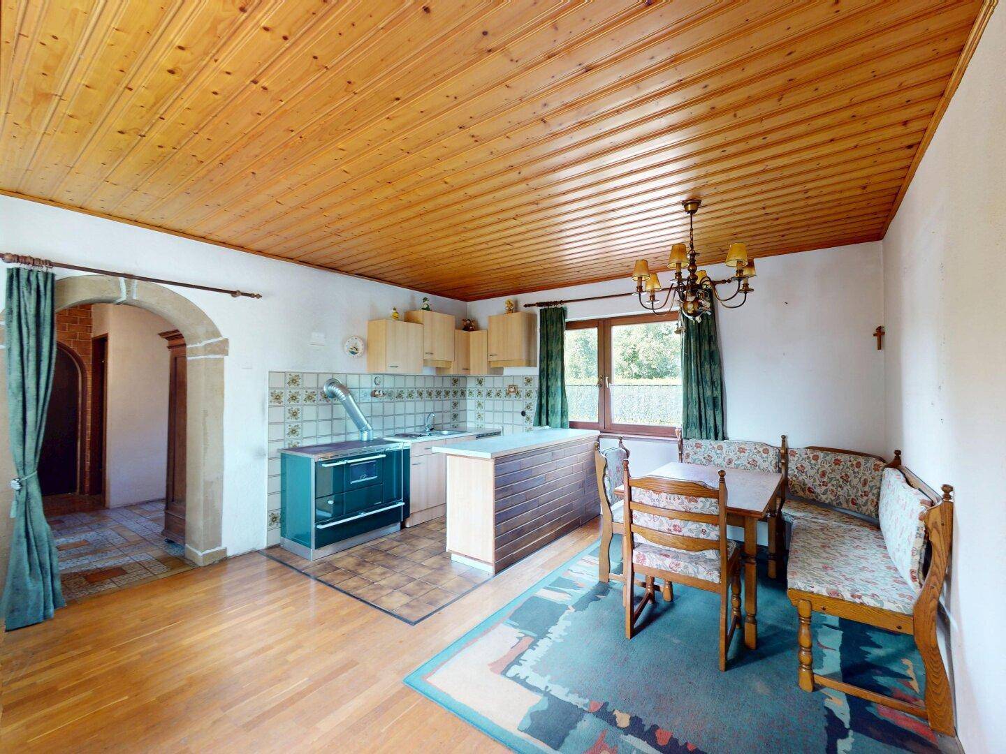 Gemütliche Wohnküche mit Holzboden, Holzdecke und Essbereich mit traditionellen Bänken.