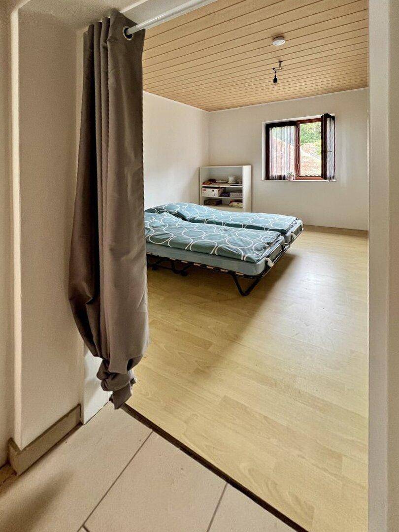 Schlafzimmer mit zwei Einzelbetten, Holzdecke und Fenster mit Blick ins Grüne.