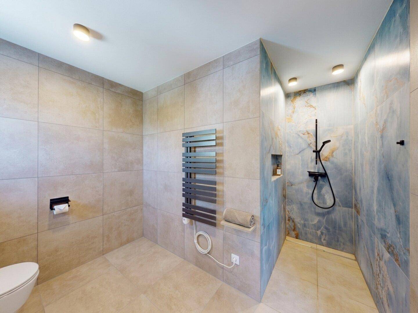 Elegantes Badezimmer mit begehbarer Dusche, blauen Akzentfliesen und modernem Design.