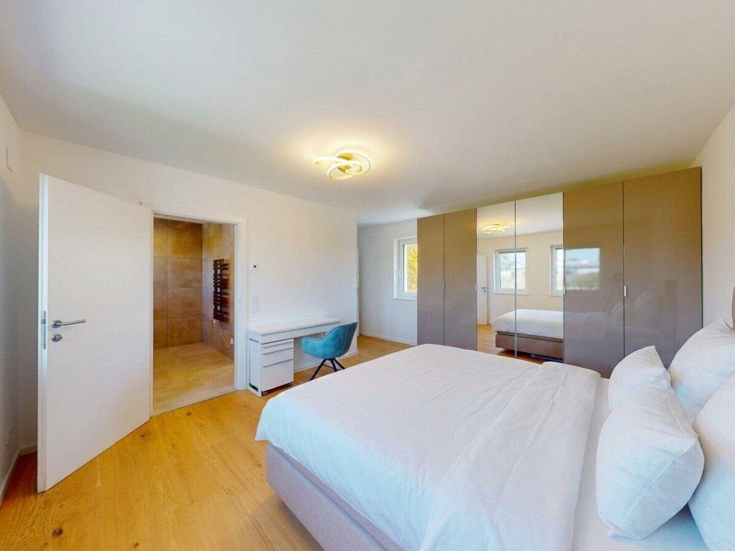 Komfortables Schlafzimmer mit großem Bett, Spiegelschränken und direktem Zugang zum Badezimmer.