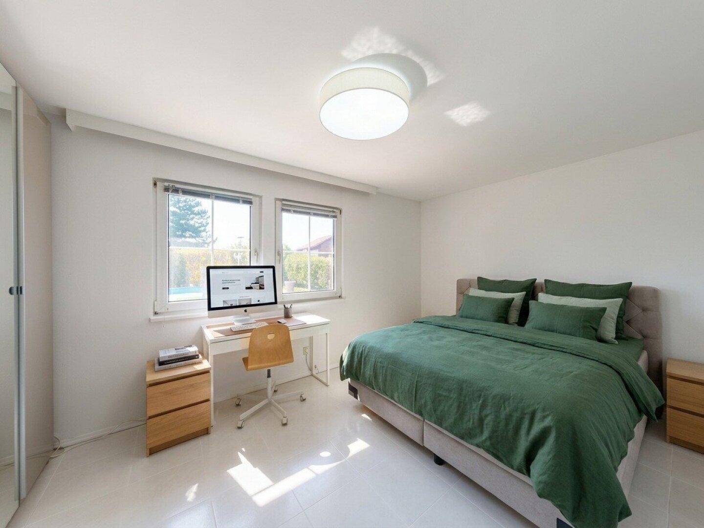 Gemütliches Schlafzimmer mit grünem Bettzeug, Schreibtisch und Blick in den Garten.