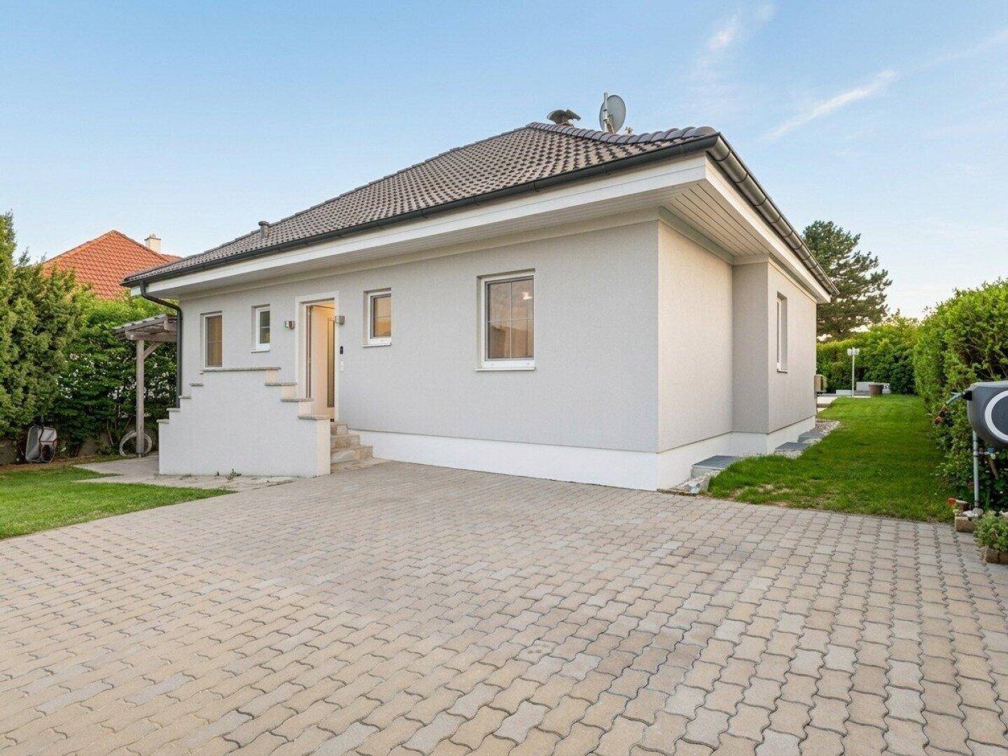 Rückansicht des Hauses mit gepflasterter Auffahrt und Zugang zum Garten.