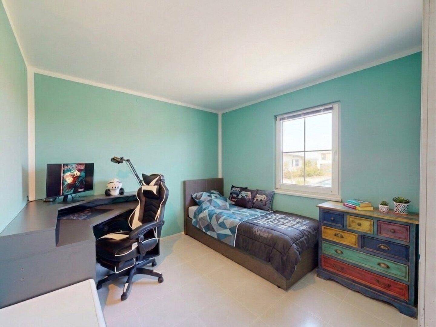 Kinderzimmer mit mintgrünen Wänden, Einzelbett, Schreibtisch und bunter Kommode.