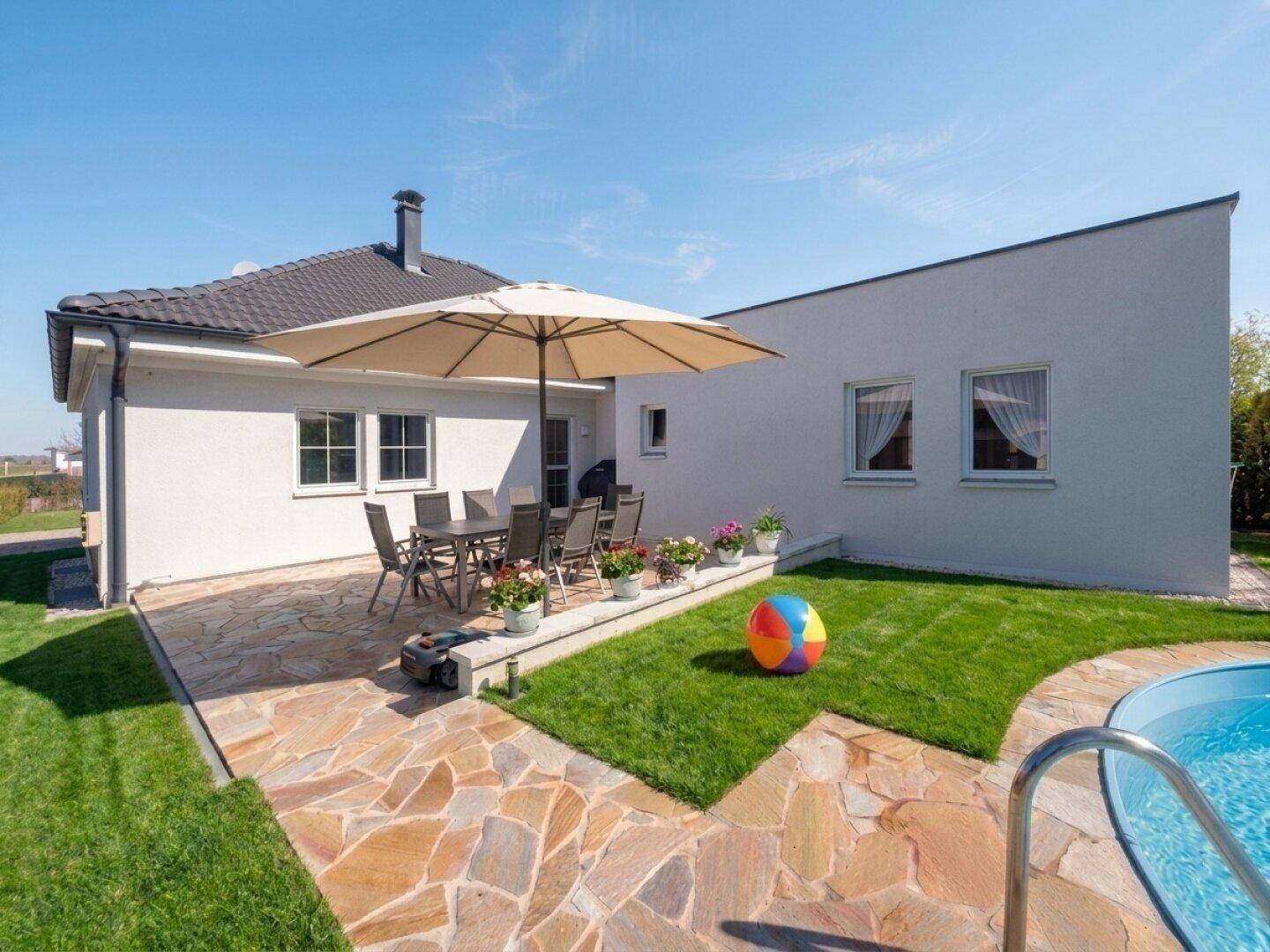 Gepflegter Gartenbereich mit Steinterrasse, Rasenfläche und einem kleinen eingelassenen Swimmingpool.