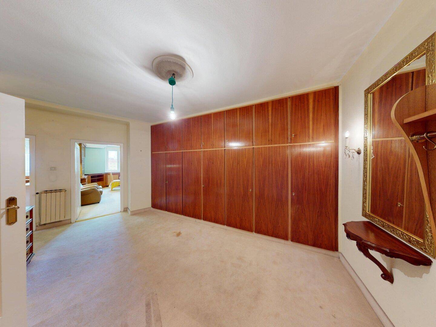 Geräumiger Flur mit großen Einbauschränken aus Holz und Zugang zu einem weiteren Zimmer.
