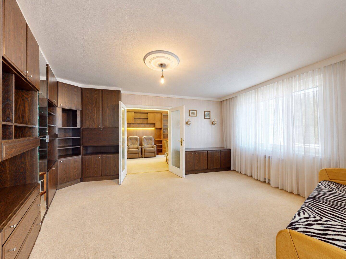 Geräumiges Schlafzimmer mit Einbauschränken und Doppeltüren, die zum Wohnbereich führen.