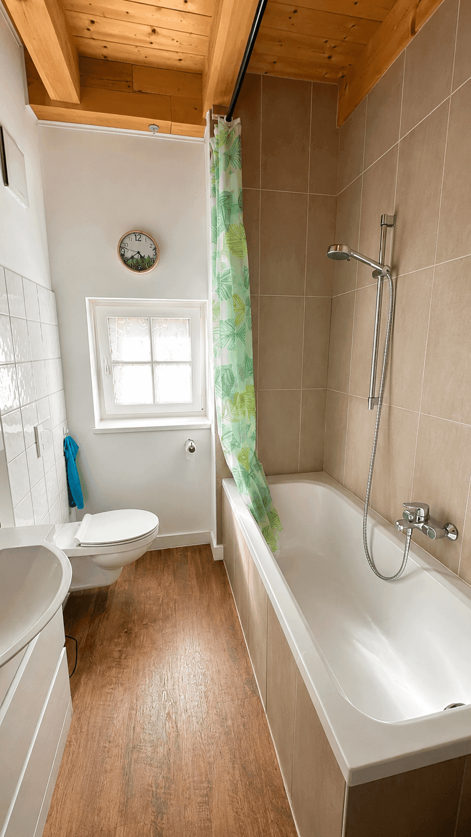 Funktionales Badezimmer mit Badewanne, WC, Waschbecken und Fenster.
