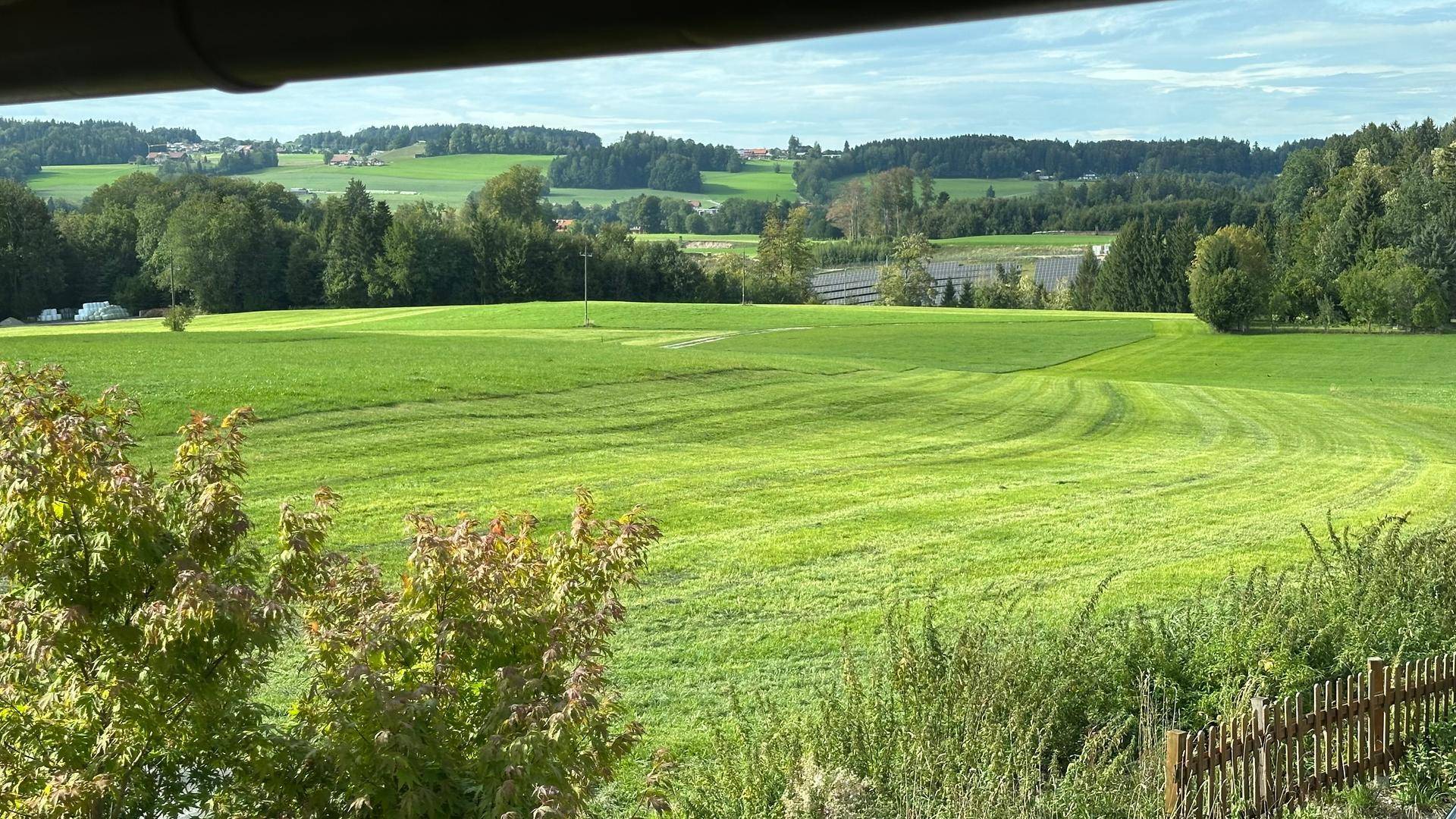 Weitläufiger Panoramablick über grüne Hügel und Felder unter einem bewölkten Himmel.