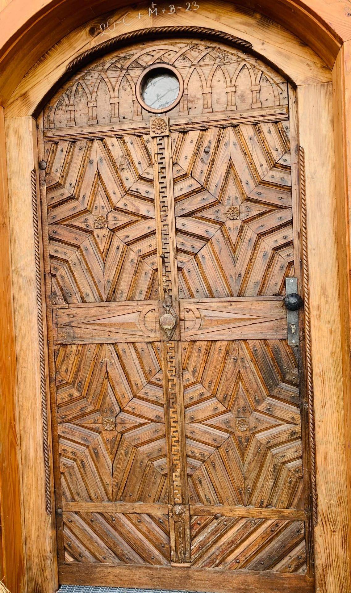 Historische, reich verzierte Holztür mit kunstvollen Schnitzereien und Metallbeschlägen.