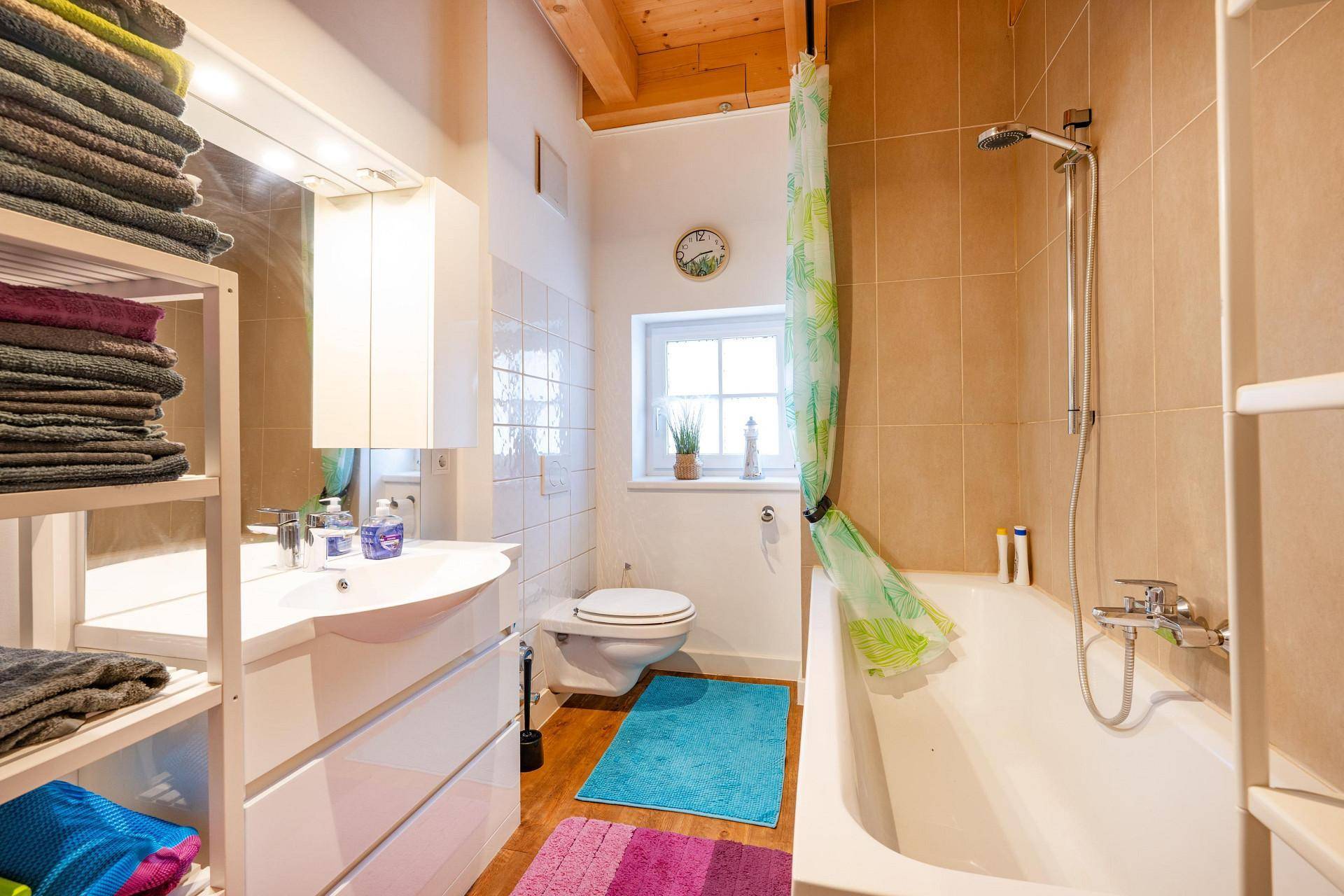 Funktionales Badezimmer mit Badewanne, Dusche, WC und Fenster für natürliche Belüftung.