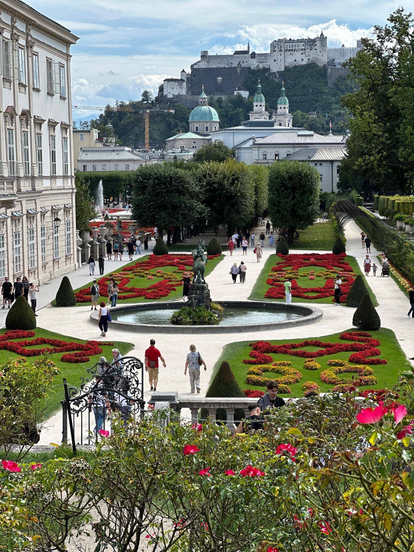 Prächtiger Garten mit Blumenbeeten, Springbrunnen und Blick auf die Festung Hohensalzburg.