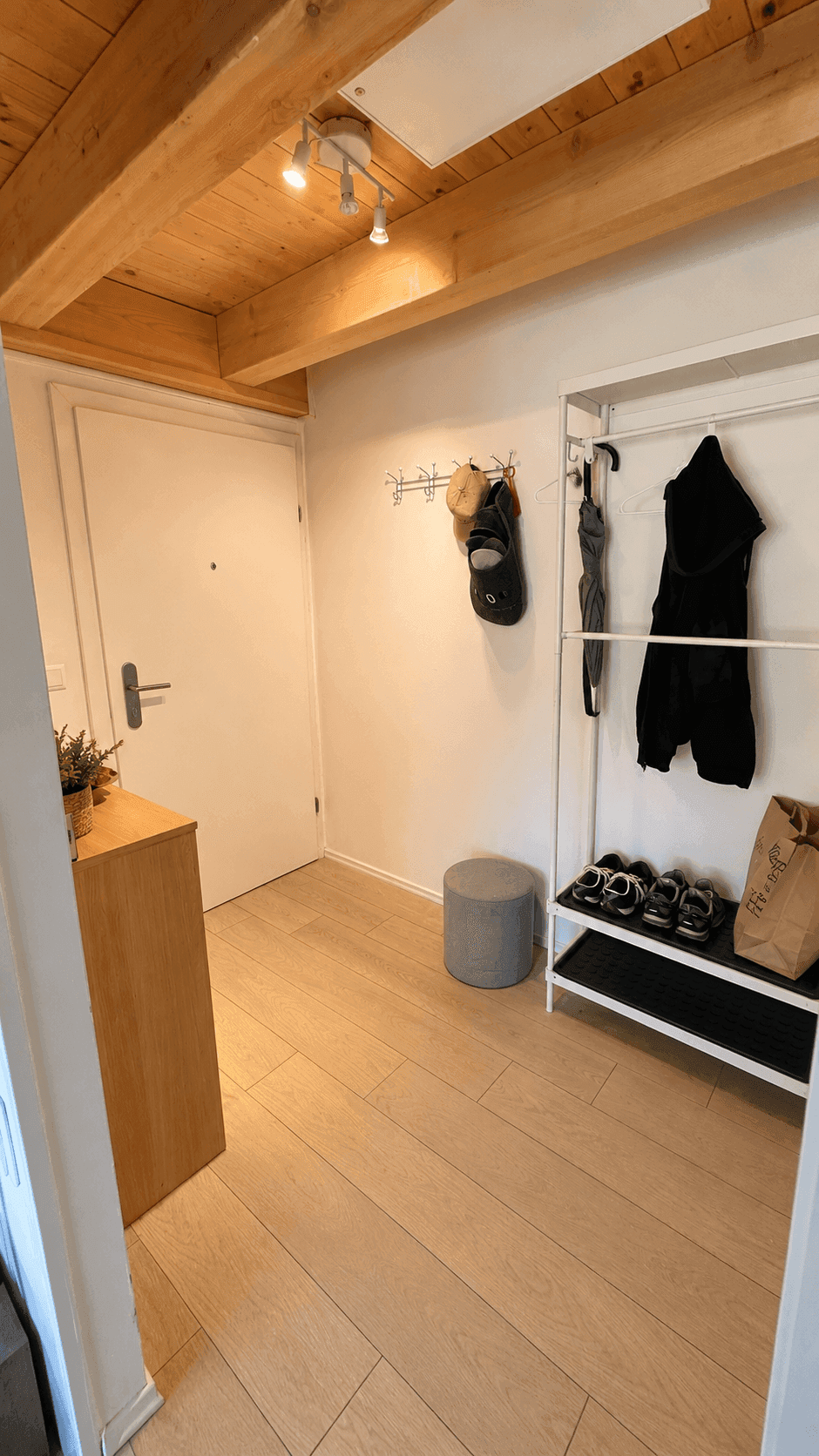 Heller Eingangsbereich mit Holzbalkendecke, Garderobe und hellem Boden.